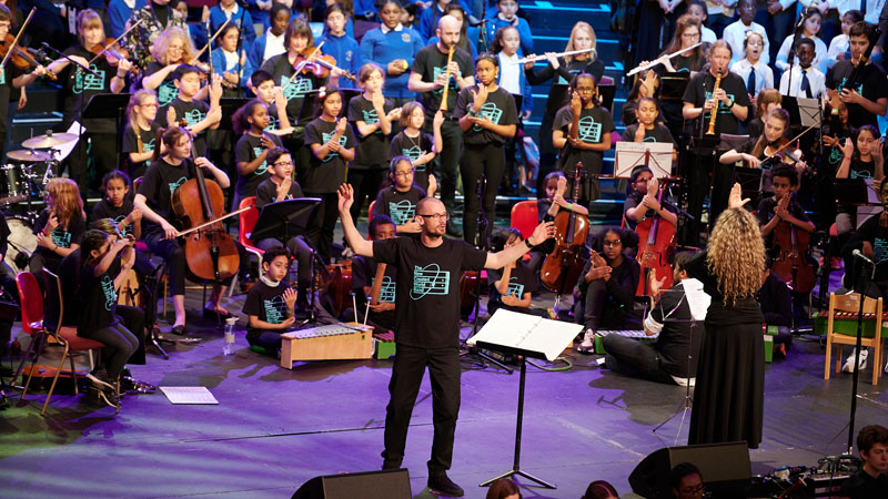 Professional musicians conducting a large group of students